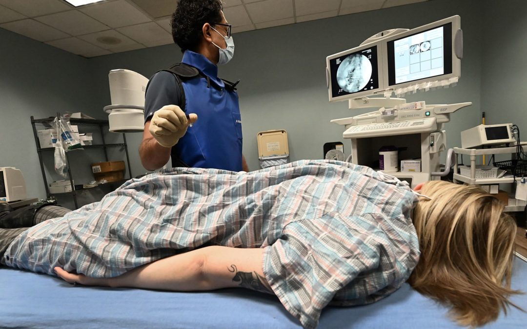 A member of the Insight medical staff analyzes an image while testing a patient, who is lying on a hospital bed in an examination room. The Flint-based medical system is expected to open a facility in a former Lincoln Park hospital in Wayne County, Michigan. Temporarily, it will be used as a COVID-19 relief treatment center.